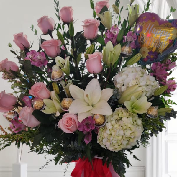 Pink roses and white lilies in a round box with a birthday balloon