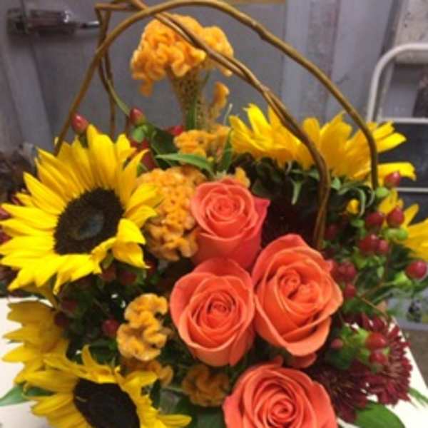 Basket arrangement with sunflowers and coral roses