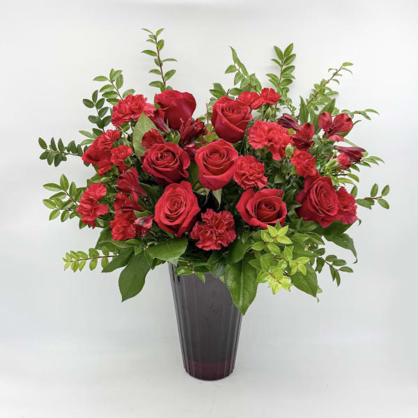 Red roses and carnations arranged in a dark vase
