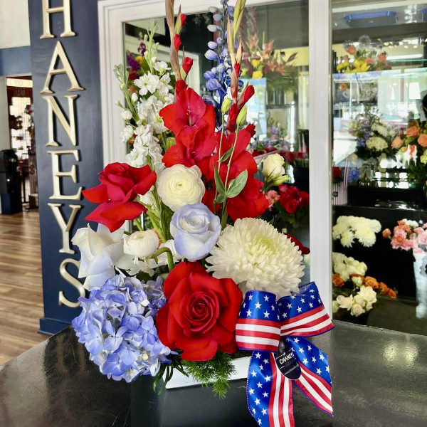 Tall red, white, and blue floral arrangement with a patriotic ribbon