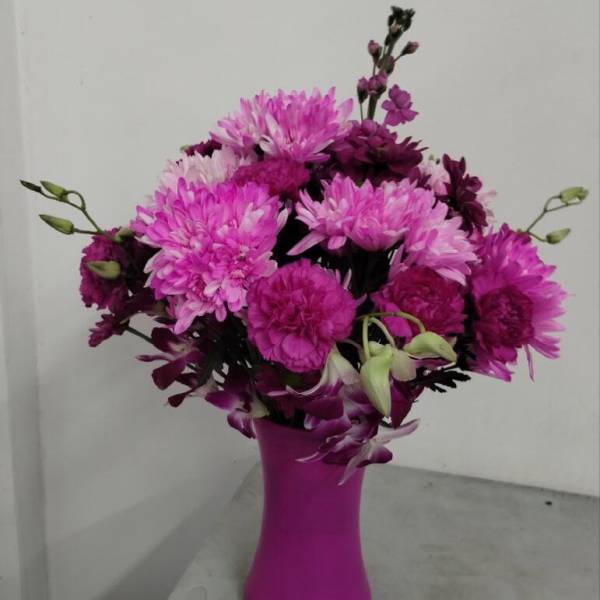 Pink and purple mixed flower arrangement in a bright pink vase