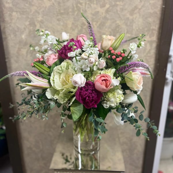 Mixed bouquet of pink, white, and purple flowers in a glass vase