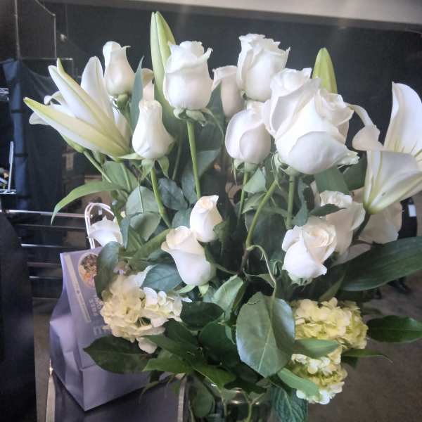 White roses and lilies arranged in a glass vase