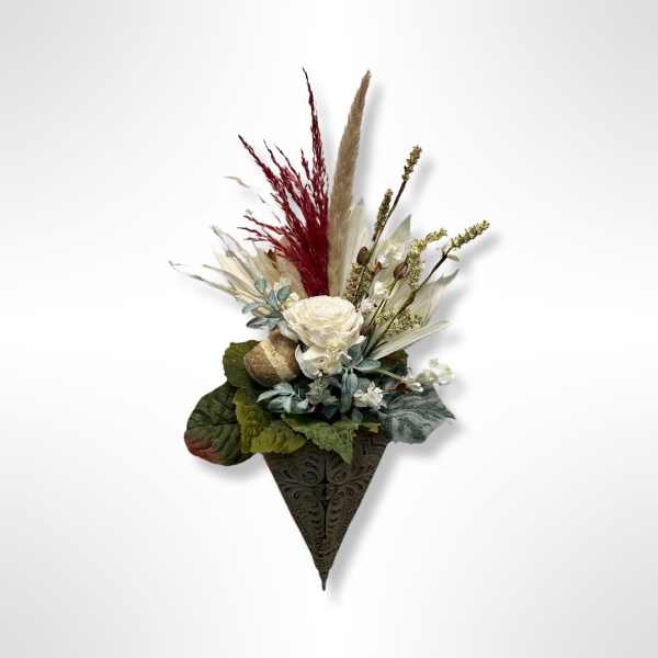 Dried floral wall arrangement with white blooms and burgundy grasses in a decorative cone holder