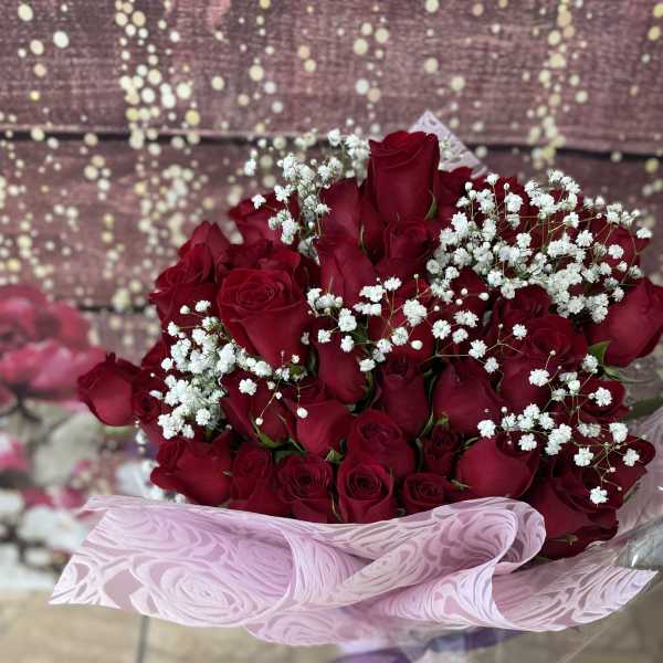 Bouquet of red roses with white baby's breath in pink wrapping