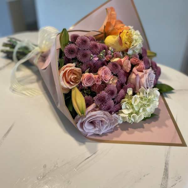 Bouquet of pink, purple, and yellow flowers wrapped in blush paper