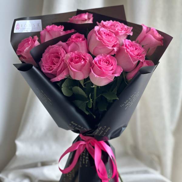 Bouquet of pink roses wrapped in black paper with a pink ribbon
