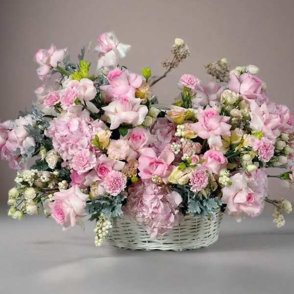 Large pink floral arrangement in a white wicker basket
