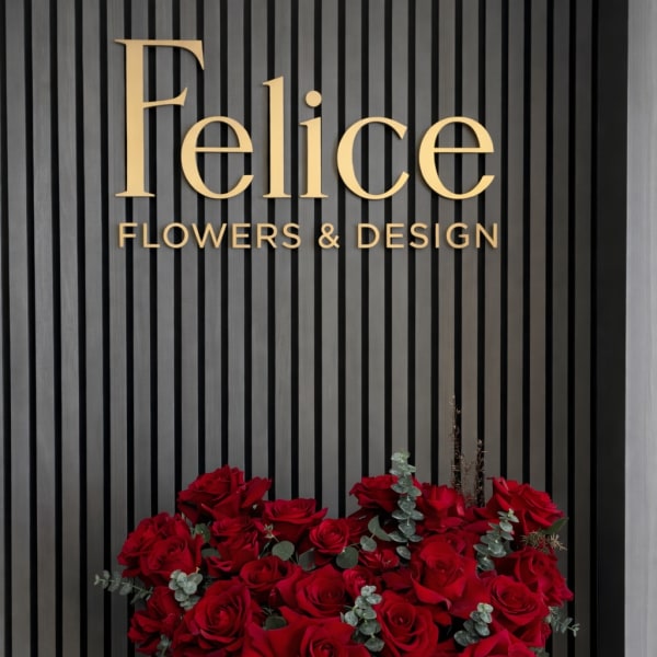 Red roses arranged in a heart-shaped box with ribbon accents