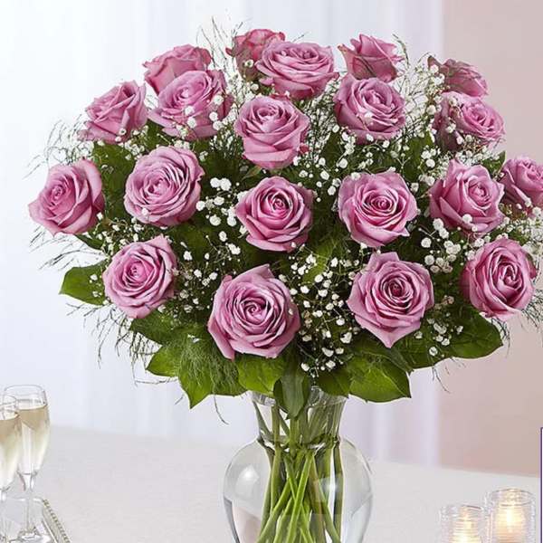 Pink roses arranged in a clear glass vase with baby's breath
