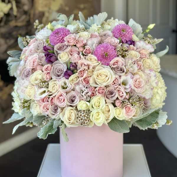 Large pastel bouquet of roses and pink blooms in a pink cylinder box