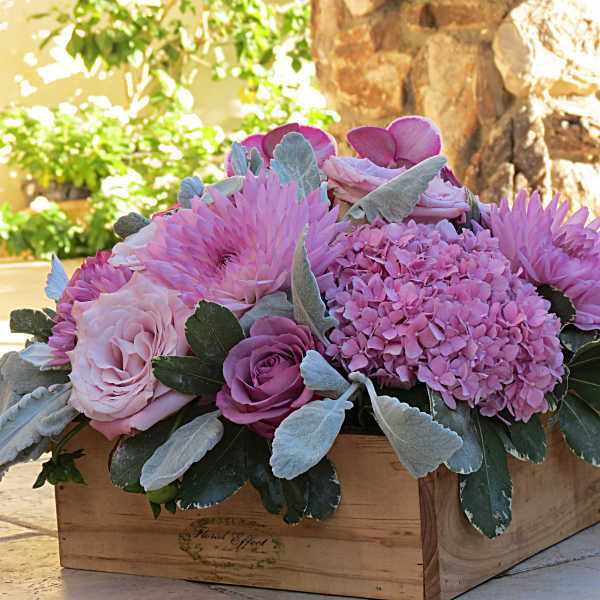 Pink floral arrangement in a wooden box with roses and hydrangea