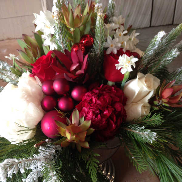 Holiday bouquet with red and white flowers, pine branches, and red ornaments