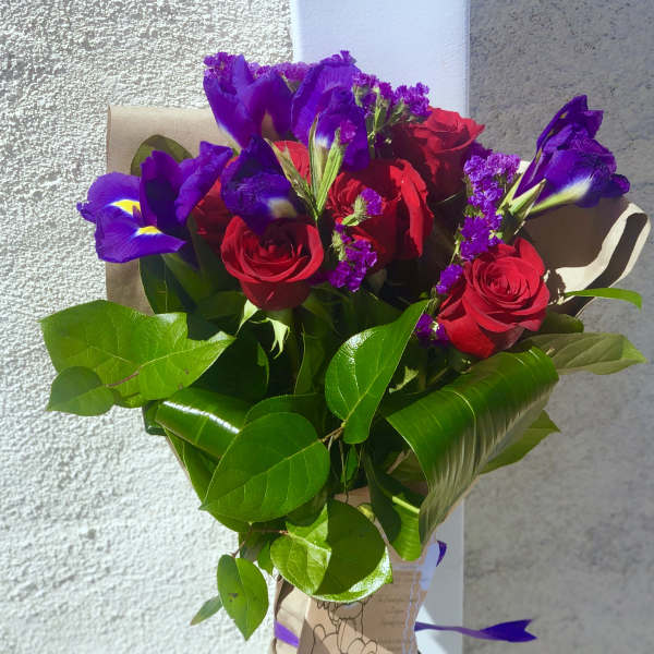 Bouquet of red roses and purple irises wrapped in brown paper