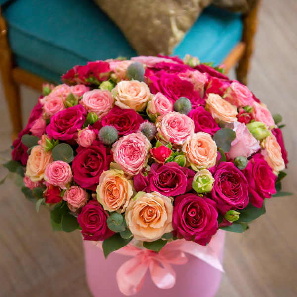 Bouquet of pink, peach, and magenta roses in a pink hatbox