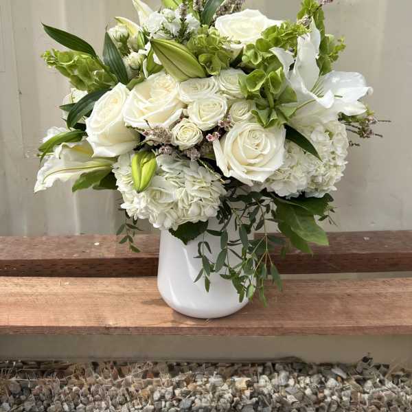 White roses and lilies arranged in a white vase