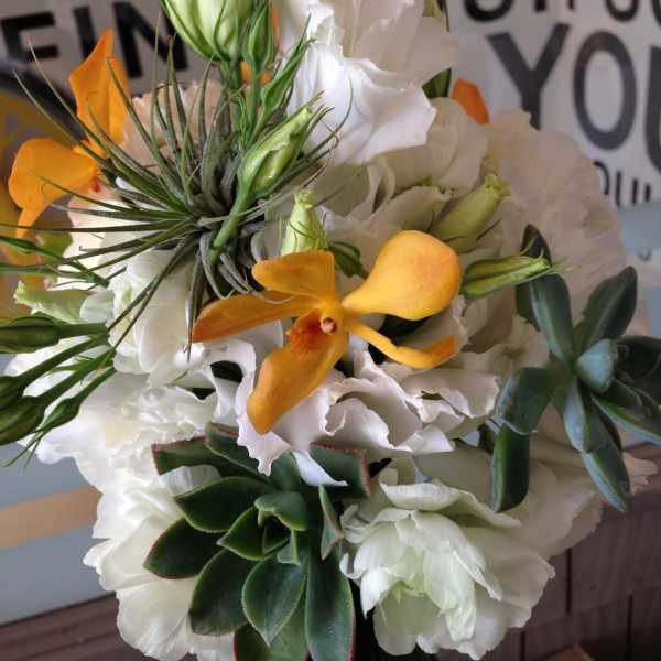 Bouquet of white flowers with orange orchids and succulents