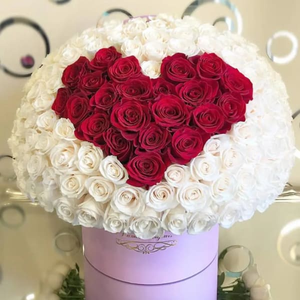 Large heart-shaped red and white rose arrangement in a round hatbox