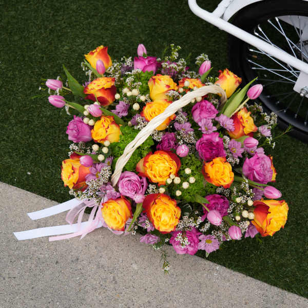 Basket of pink and yellow roses with tulips and daisies