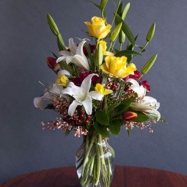 Mixed bouquet of yellow roses and white lilies in a glass vase