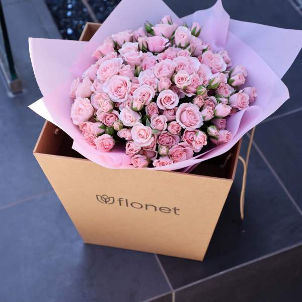 Bouquet of pale pink roses wrapped in pink paper inside a gift box