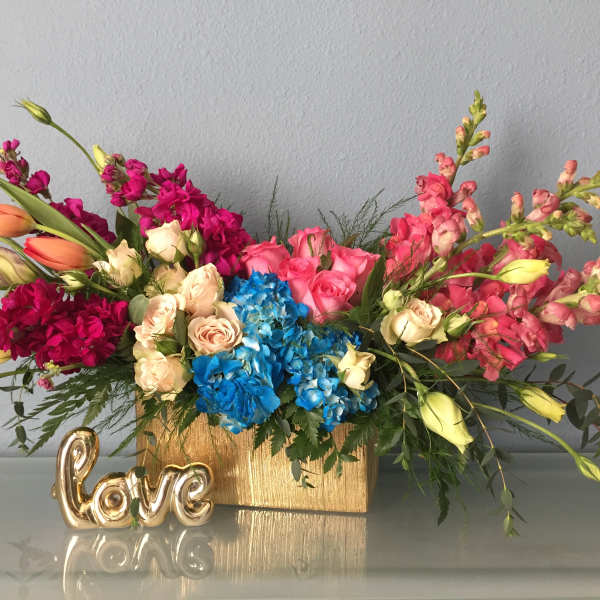 Colorful flower arrangement in a gold box with a small gold "love" decoration