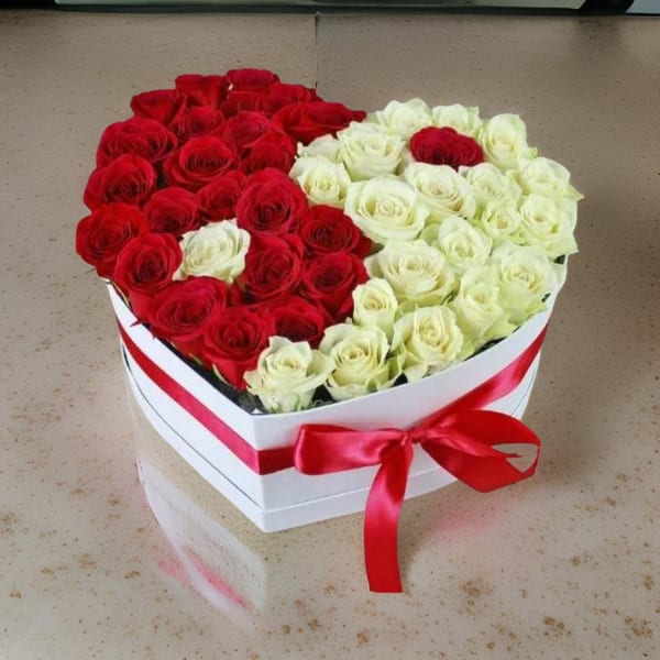 Heart-shaped box of red and white roses with a red ribbon