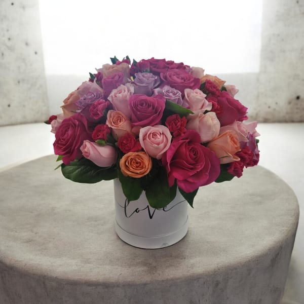Bouquet of pink, purple, and peach roses in a white hat box