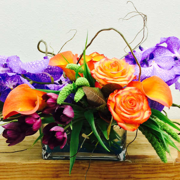 Orange roses and purple orchids in a glass vase