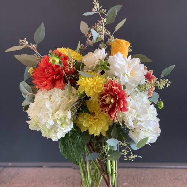 Colorful bouquet of dahlias and hydrangeas in a clear glass vase