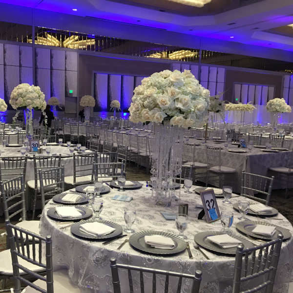 White floral centerpieces on round banquet tables in a reception hall
