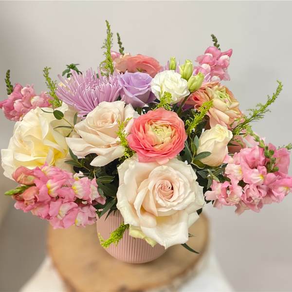 Pastel bouquet of roses, ranunculus, and snapdragons in a pink vase