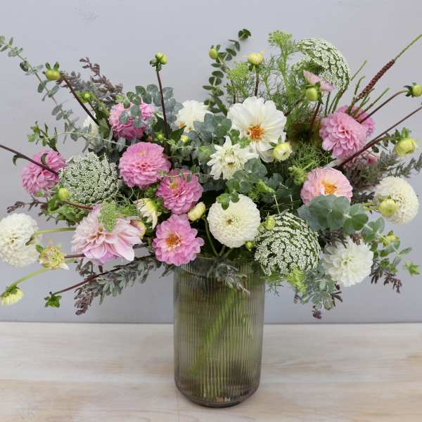 Tall glass vase arrangement of pink and white dahlias with airy filler flowers