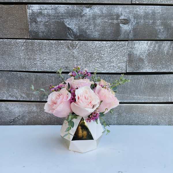 Pink roses arranged in a white geometric vase