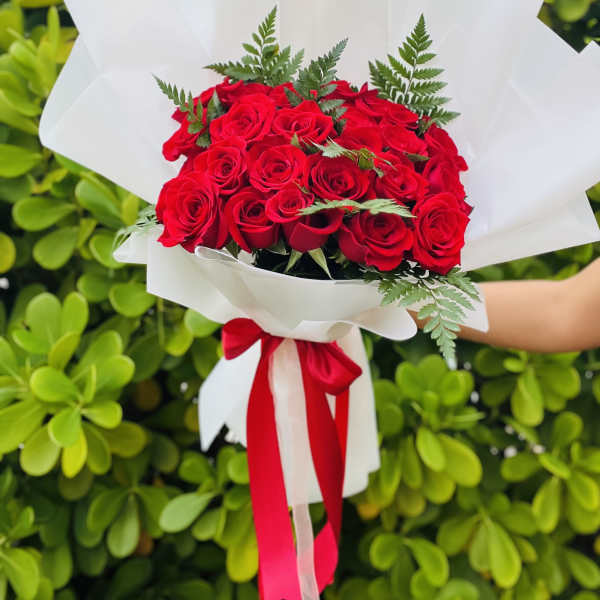 Bouquet of red roses wrapped in white paper with a red ribbon