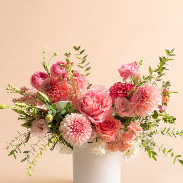Pink floral arrangement in a white vase with roses and dahlias