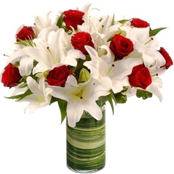 Red roses and white lilies arranged in a green glass vase
