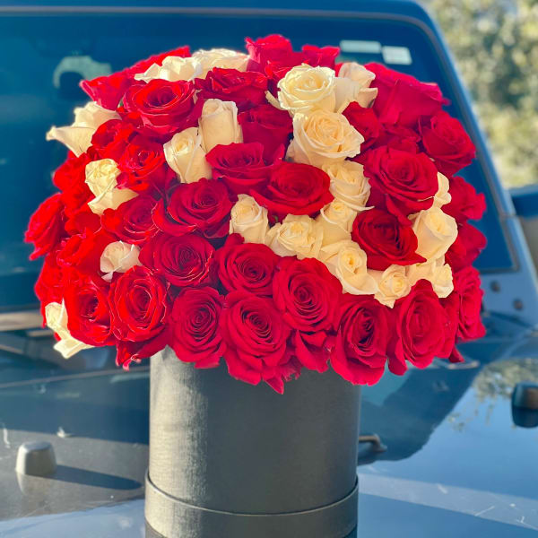 Round bouquet of red and white roses in a black box