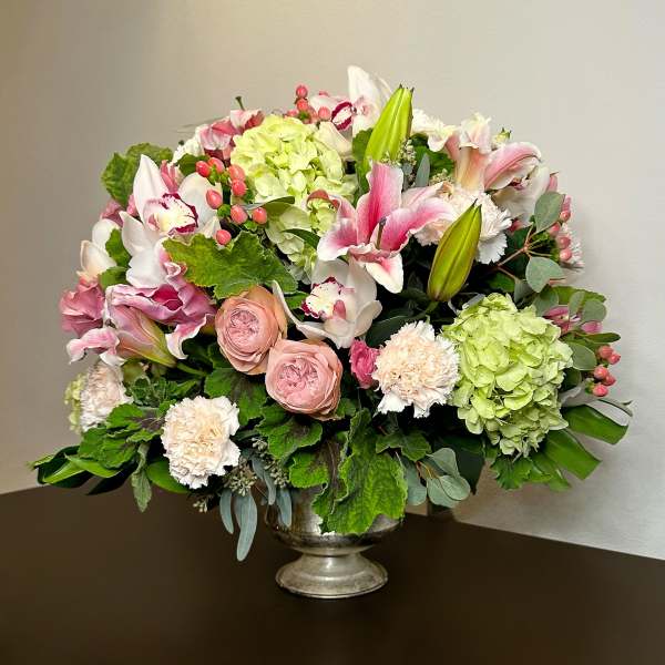 Mixed pink and white floral arrangement in a silver pedestal vase