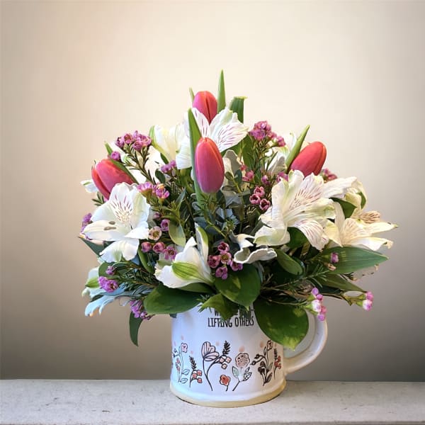 Bouquet of pink tulips and white lilies in a floral mug vase