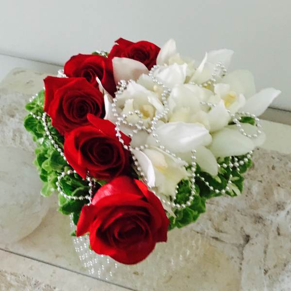 Red roses and white orchids arranged with pearl strands