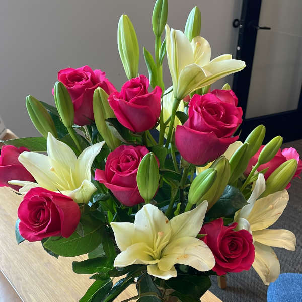 Pink roses and white lilies arranged in a clear glass vase