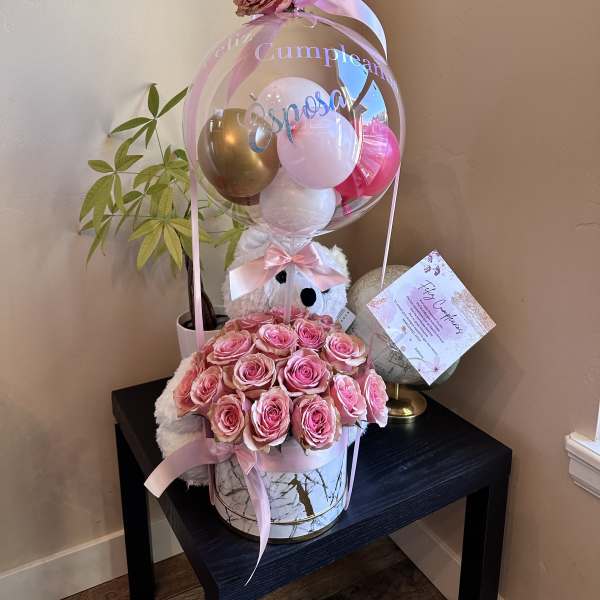 Pink rose arrangement with balloons and a teddy bear in a gift box