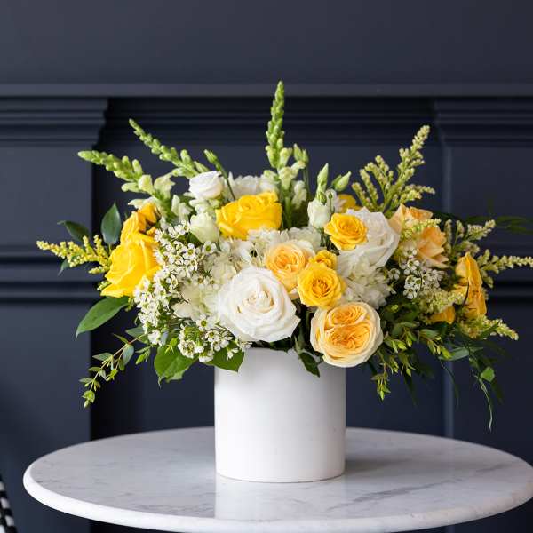 Yellow and white roses arranged in a white vase