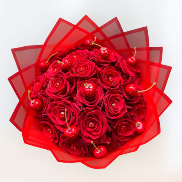 Red rose bouquet with cherries wrapped in translucent red paper