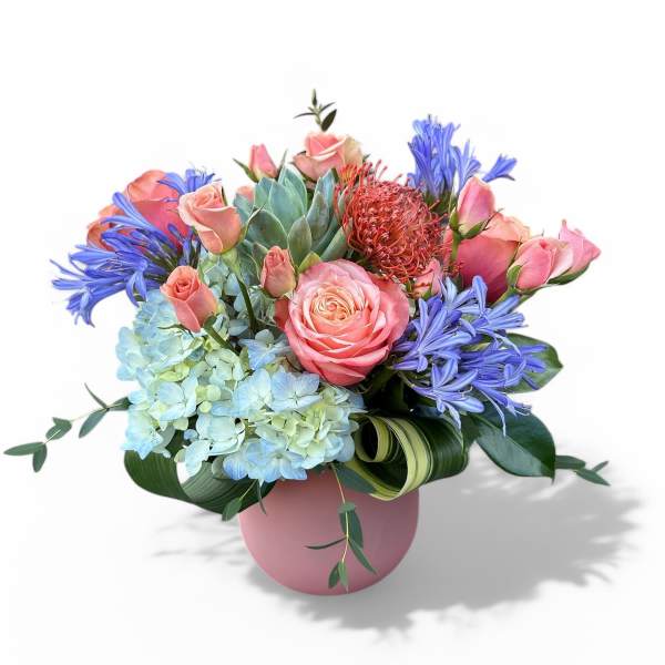 Pink roses and blue flowers arranged in a pink vase