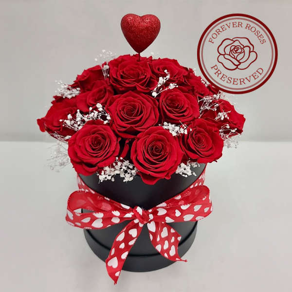 Red roses in a black hatbox with a heart topper and red ribbon