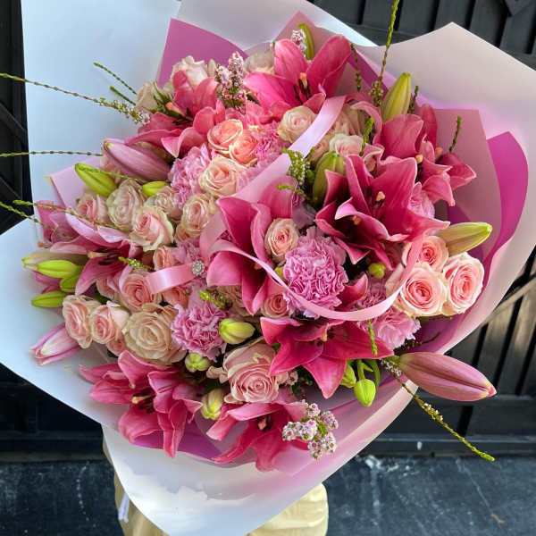 Pink bouquet with roses, lilies, and carnations wrapped in white and pink paper