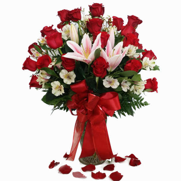 Bouquet of red roses and pink lilies in a glass vase with a red ribbon