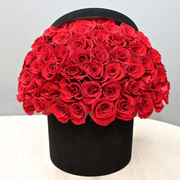 Dome of red roses arranged in a round black hatbox-style container